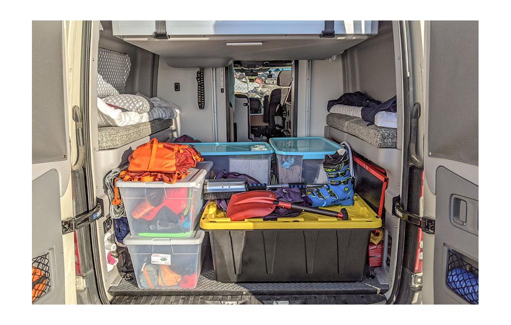 Storage bins with ski boots and other snow gear in the back of the Winnebago Revel.