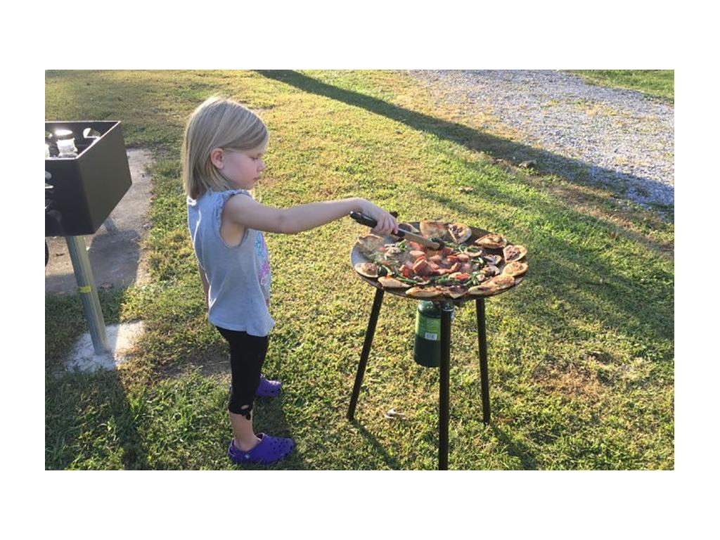 Young girl using tongs to flip food on skottle