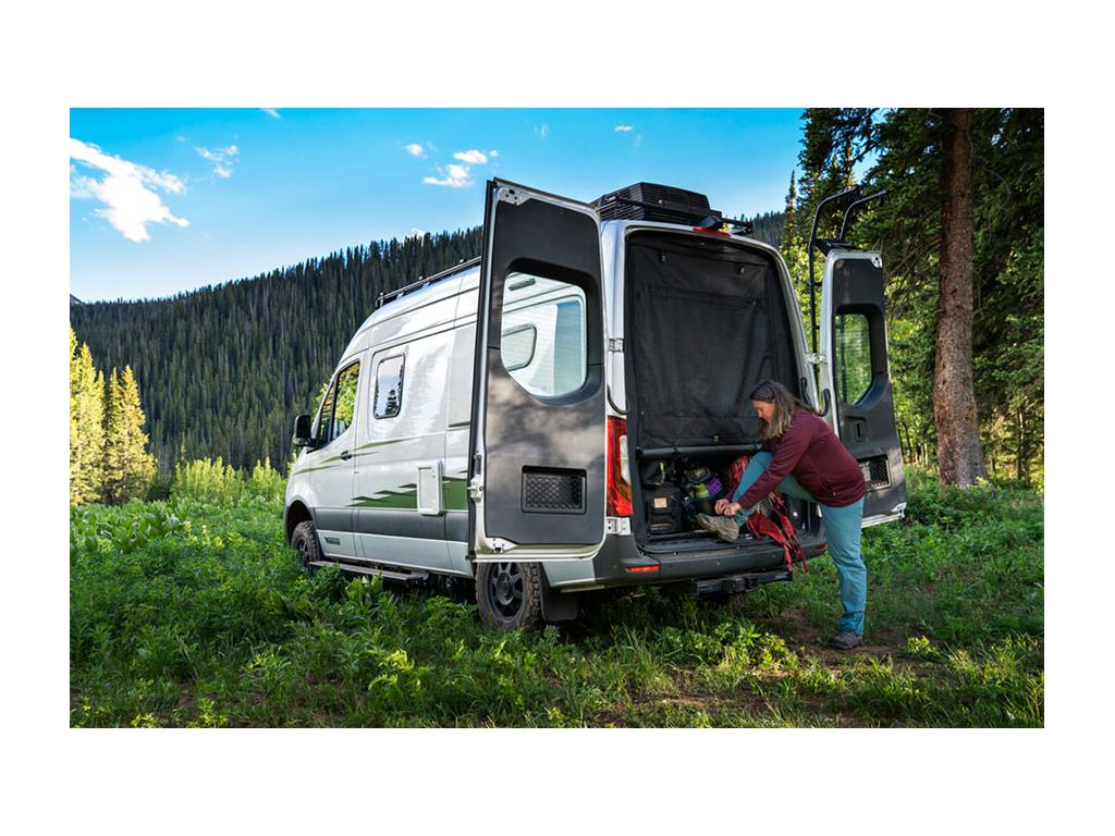 Kathy tying shoe on back of Revel with rear doors open