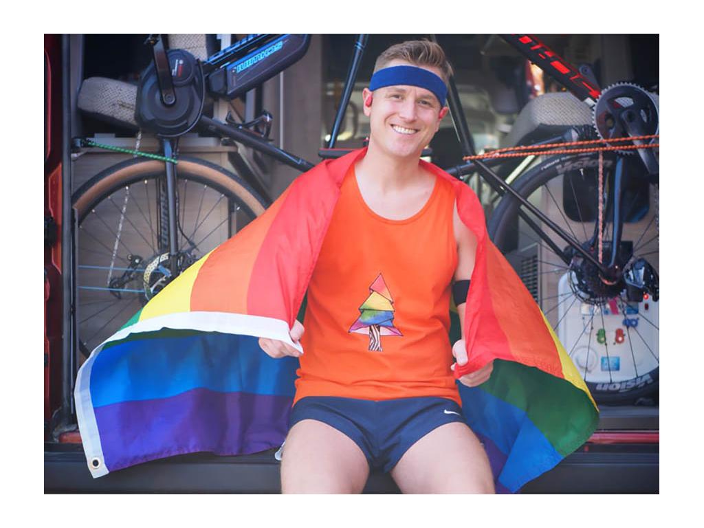 Mikah sitting on back of Solis full of bikes. Mikah has pride flag draped over shoulders