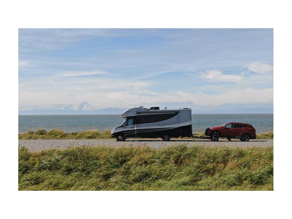 Navion pulling tow car down road along water