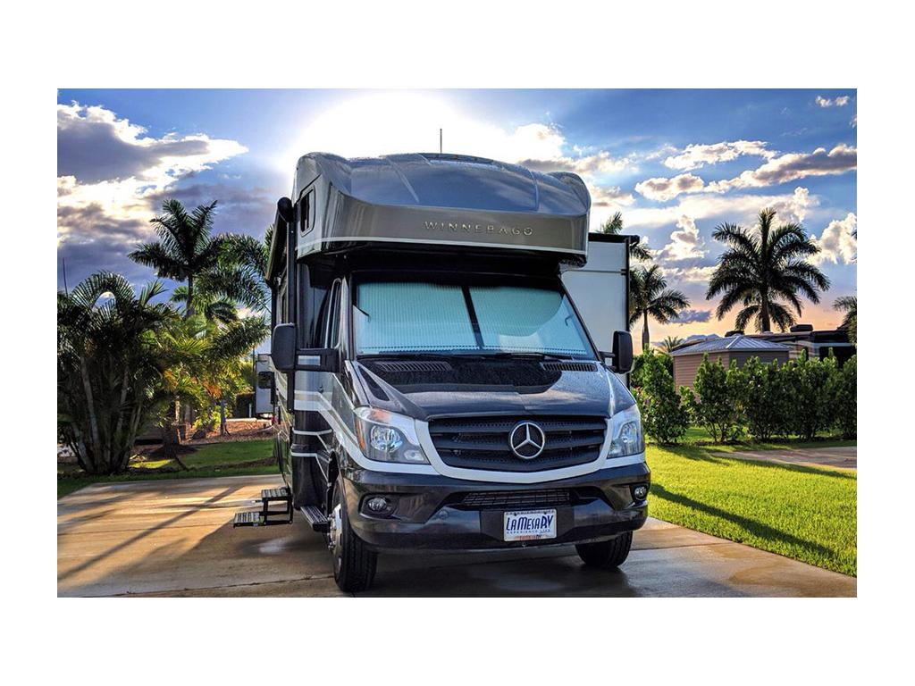 Navion parked on concrete at campground with palm trees in background