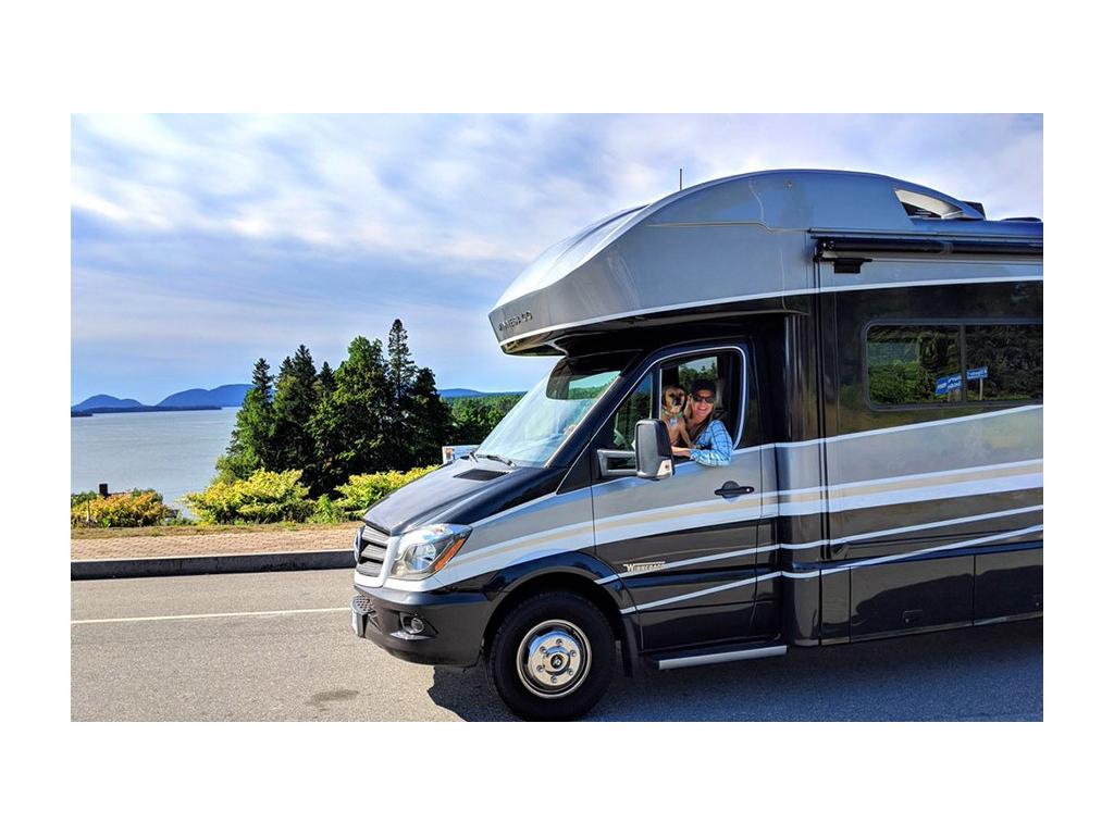 Katelyn Newstate driving Navion with dog on lap smiling out window