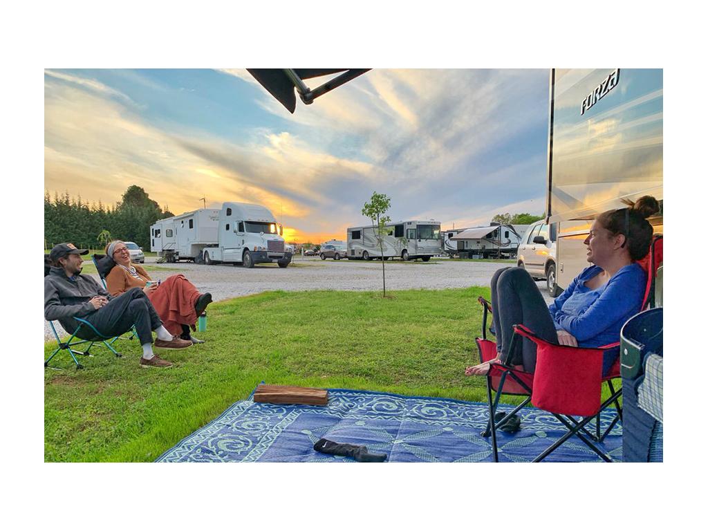 Alyssa sitting in a chair in front of Forza with two friends sitting in chairs at a distance