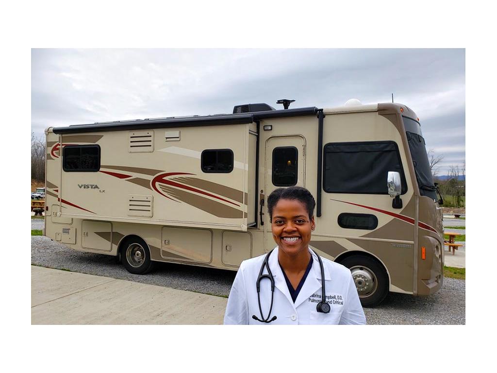 Sabrina standing in white doctor coat in front of Winnebago Vista