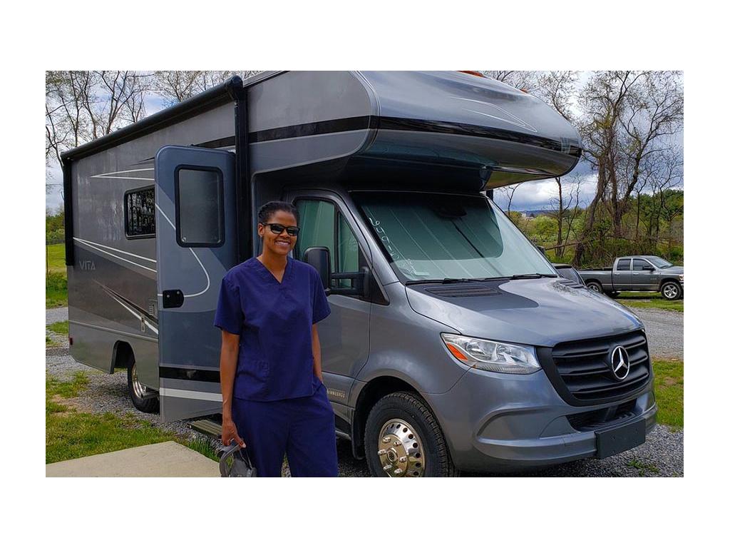 Sabrina wearing blue scrubs standing in front of Winnebago Vita