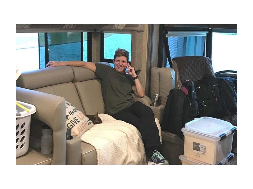 Ann sitting on couch with two plastic containers full of paperwork in front of her