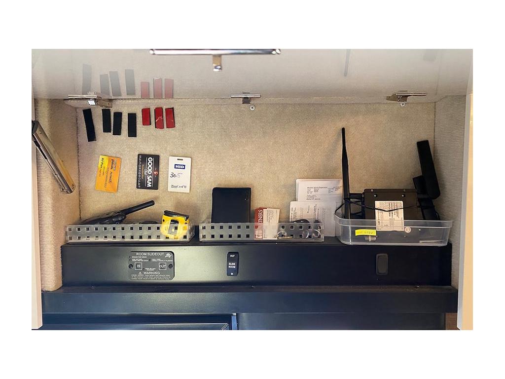 Cabinet full of miscellaneous items stuck to tan carpeted wall with Velcro