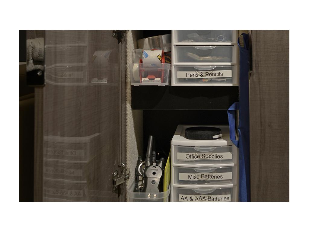 Plastic organized bins of pens and pencils, office supplies, and batteries