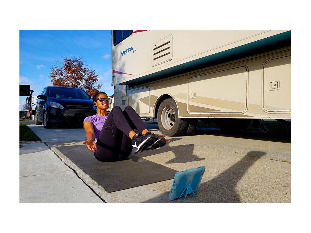 Sabina sitting next to Vista on a yoga mat using iPad for a workout