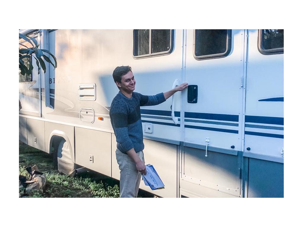 Jessie opening RV door while holding a stack of mail