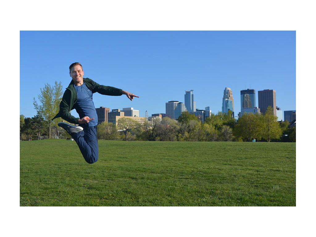 Mikah jumping in air pointing to buildings in City Park