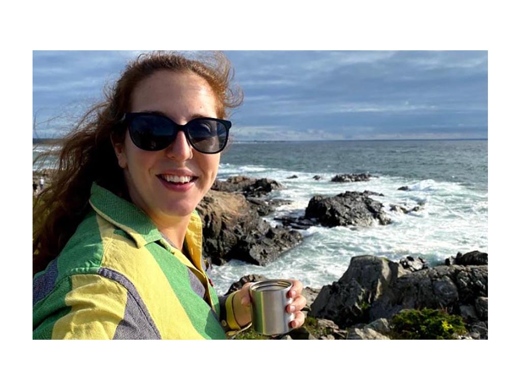 Shanae holding a cup watching the waives in Maine