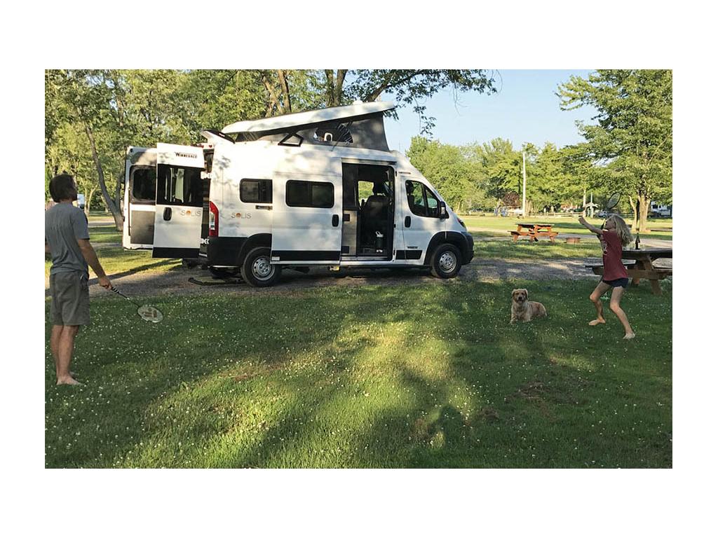 Jason and Mary playing badminton while Bennett lays in the grass