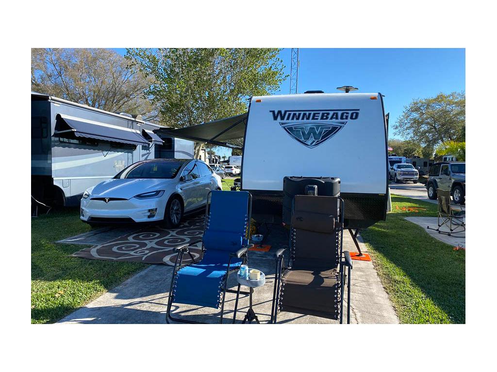 Tesla parked next to Micro Minnie at campsite with two camp chair out in front