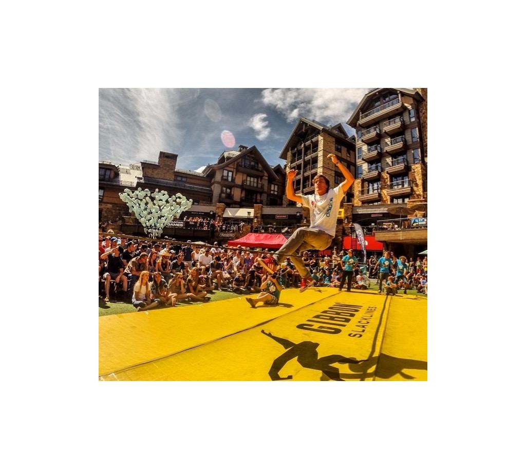 Crowds gathered watching a man go across slackline
