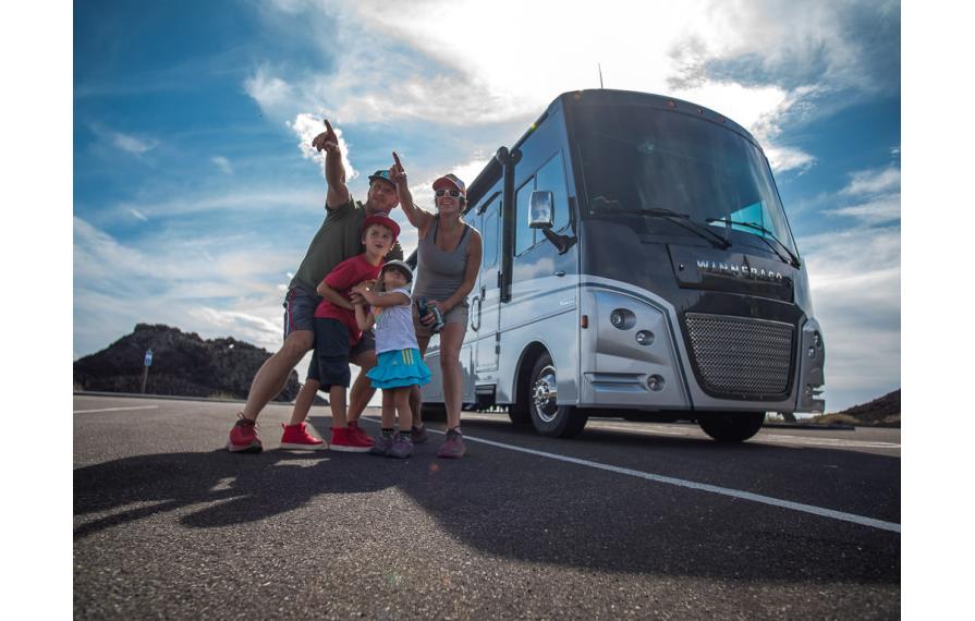 Pyke family outside their Winnebago Adventurer pointing to something in the distance