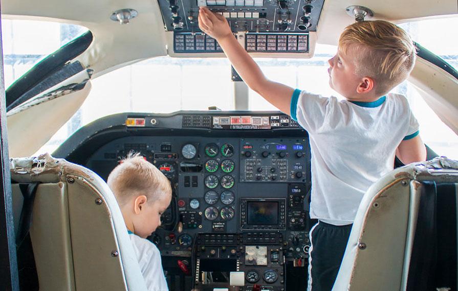 The boys playing in the cockpit of an airplane at the Kansas Aviation Museum