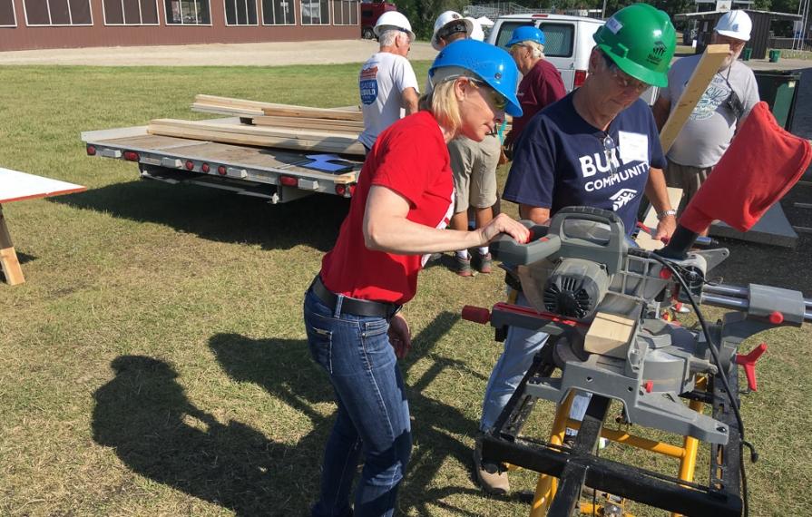 Two individuals cutting wood for the shed