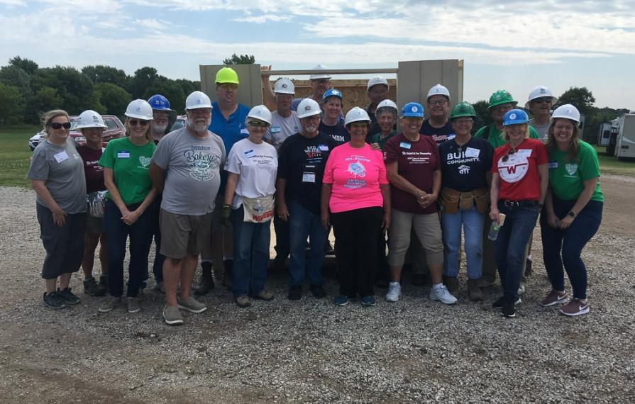 RV Care-A-Vanners huddled in front of shed smiling
