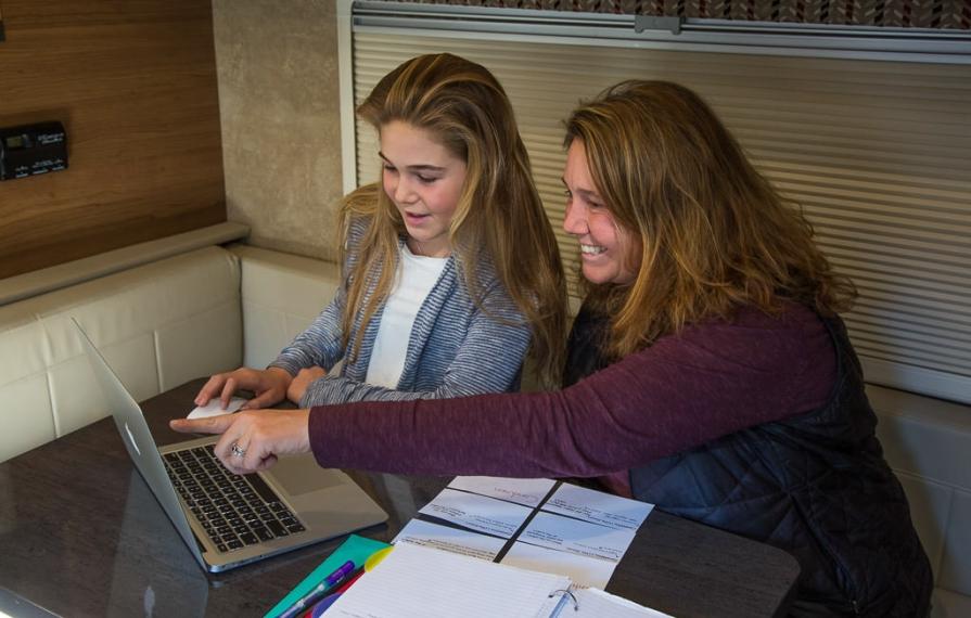 Abby and Kathy sitting at dinette doing school work on laptop