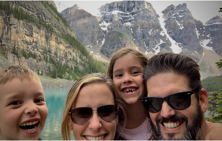 Toste family taking selfie in front of blue water and mountains