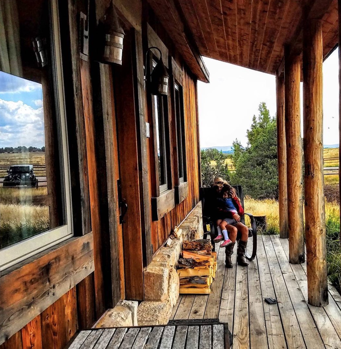 Person holding child on deck of a rustic looking building.