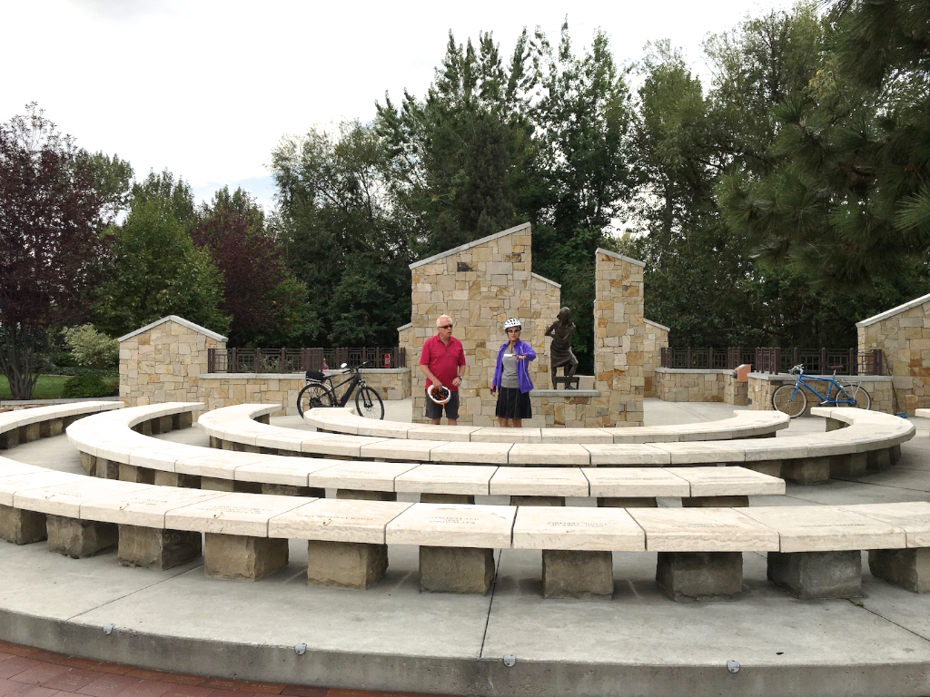 Two people gathered at the Anne Frank memorial with bikes resting against the side. 