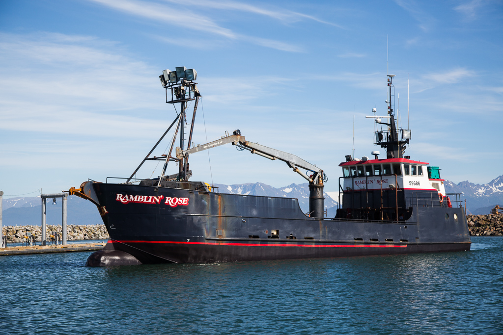 The Ramblin' Rose, crab boat on Discovery Channel's Deadliest Catch, on the water with mountains in the background.
