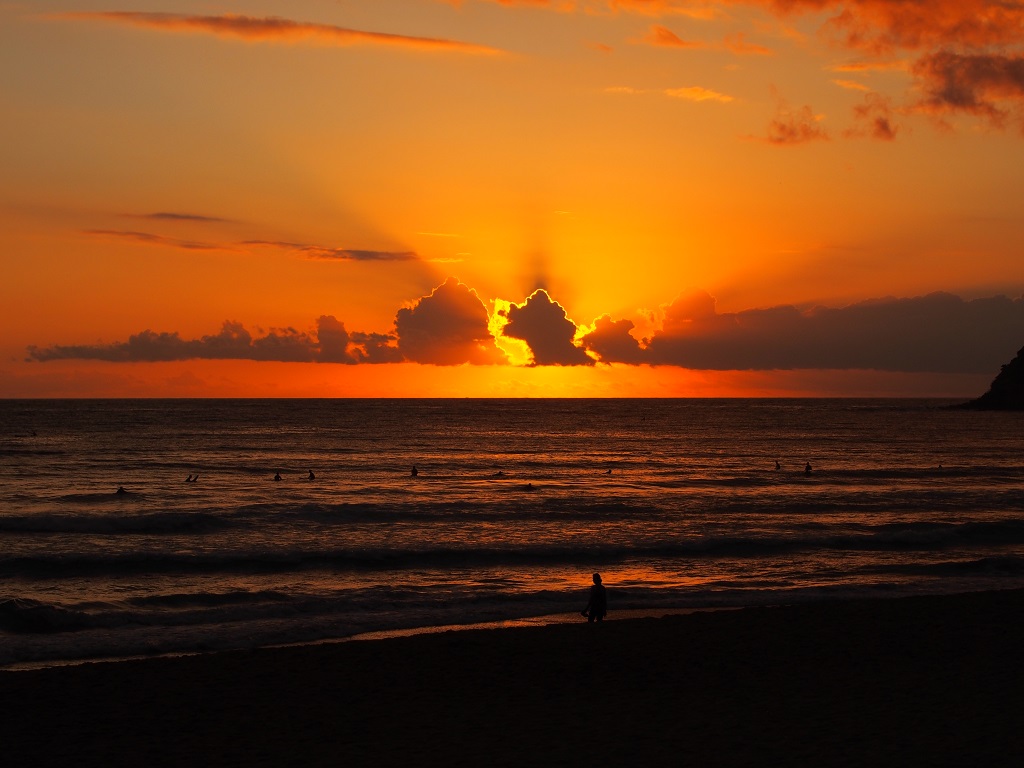 Water rippling beneath a magnificent sunset as sun dips behind the clouds.  