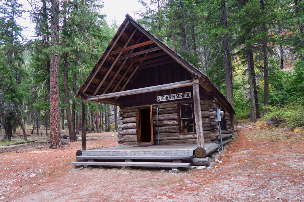 Log built Stehekin Schoolhouse among the trees.
