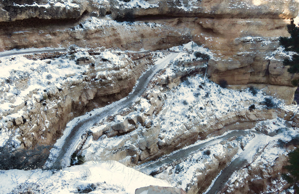 Ice and snow covered switch back hiking path down the side of the rocky canyon.