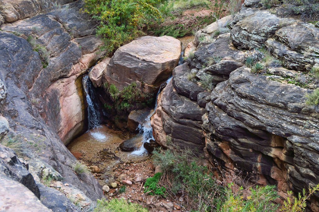 Looking down to a small stream of water pouring over a rock formation.
