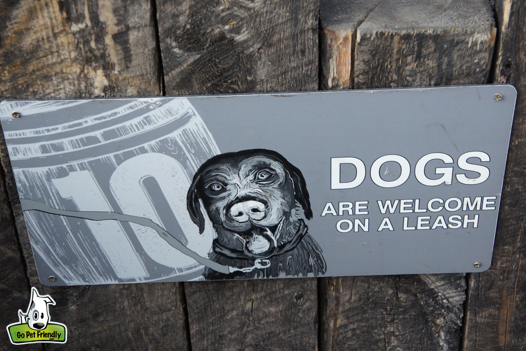Sign on fence that reads "Dogs are welcome on a leash."