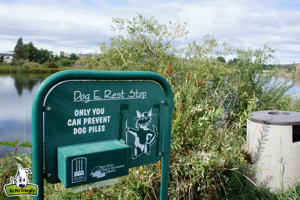 Sign with dog waste disposal bags and a trash can.