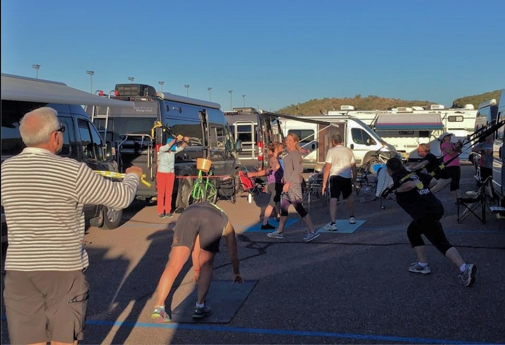 Group of people exercising among motorhomes.