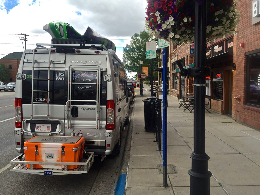 Winnebago Travato in parking spot on the street in a quaint downtown.