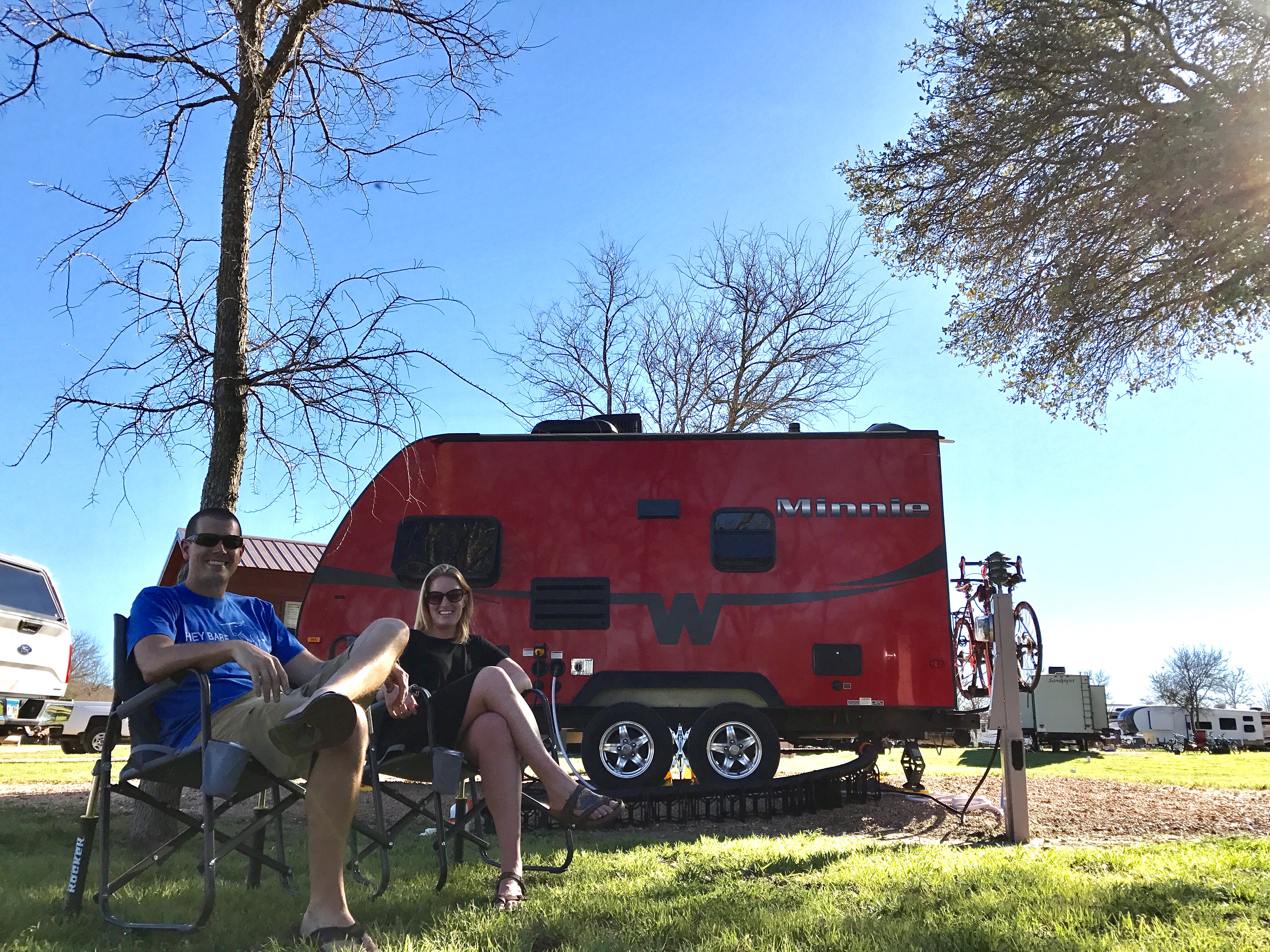 Couple sitting in lawn chairs outside their Winnebago Minnie towable.
