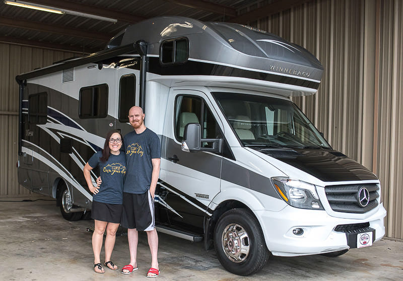Couple standing outside their Winnebago View.