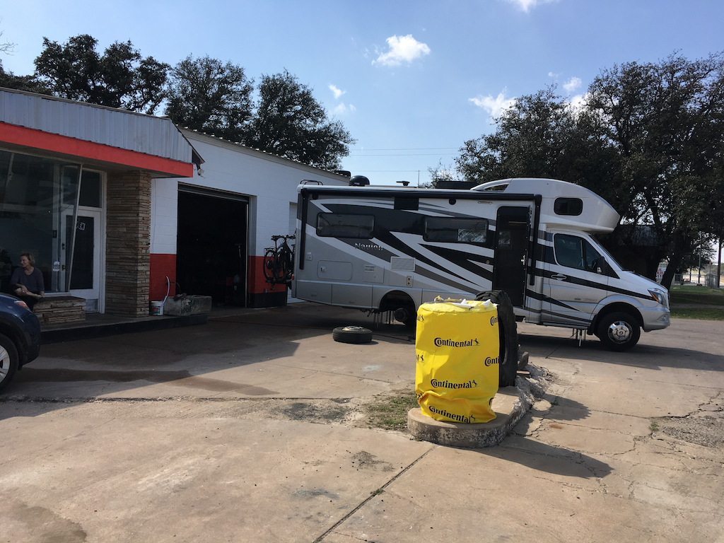 Winnebago Navion parked outside a tire shop.