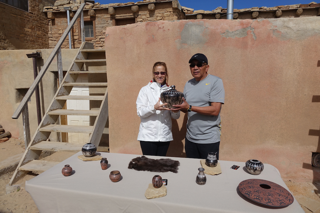 Woman standing next to artist while holding unique pottery piece.