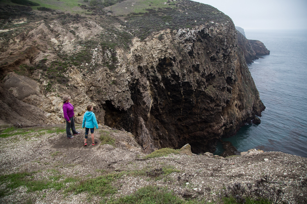 Kathy and Abby at the edge of a cliff that drops off to the ocean below.