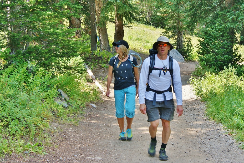 James and Stef hiking along dirt path between trees.