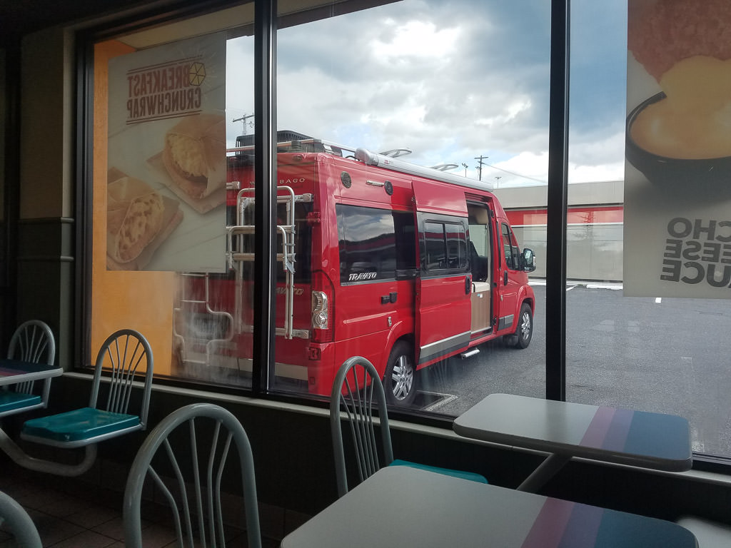 Winnebago Travato parked outside a restaurant.