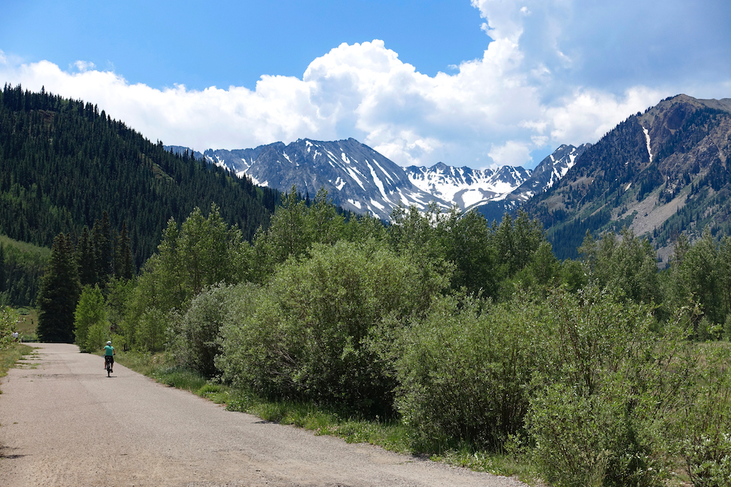 Biker on a trail with mountains in view.