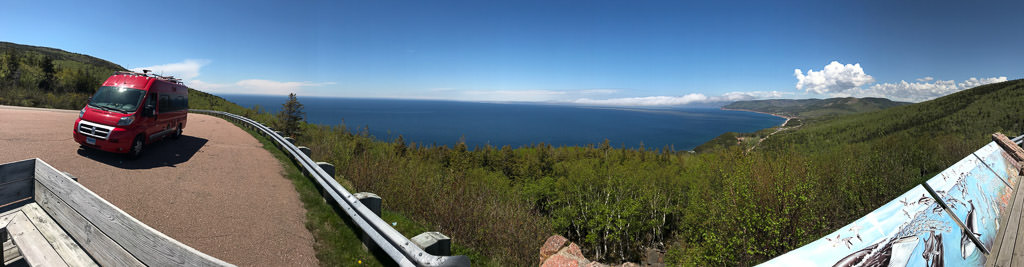 Winnebago Travato pulled to site of road at a look-out point over large body of water below.