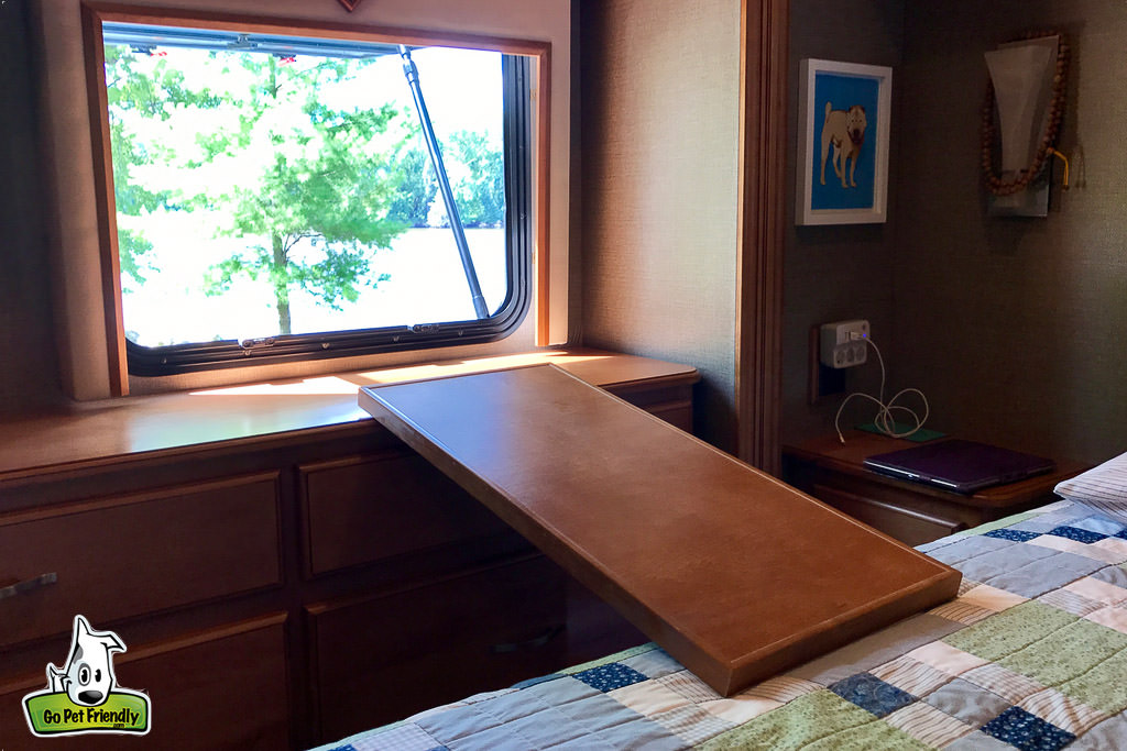 Door of fuse panel from bedroom used as a bridge between bed and cabinets below open window.