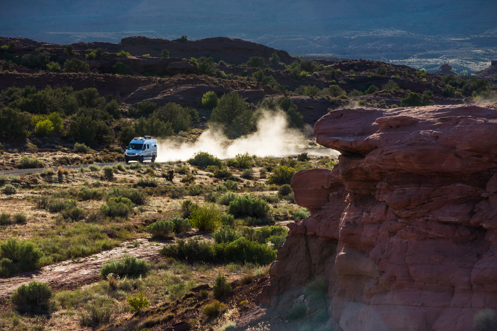 Winnebago Revel driving down a dirt path with dust flying behind it.