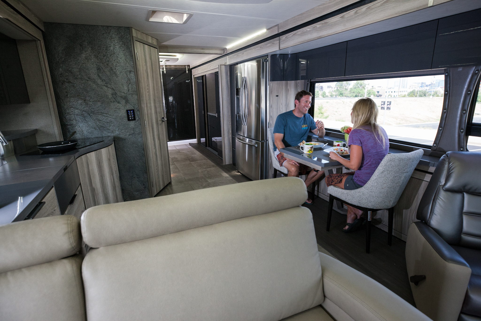 Couple eating at the dinette inside modern looking Winnebago Horizon.