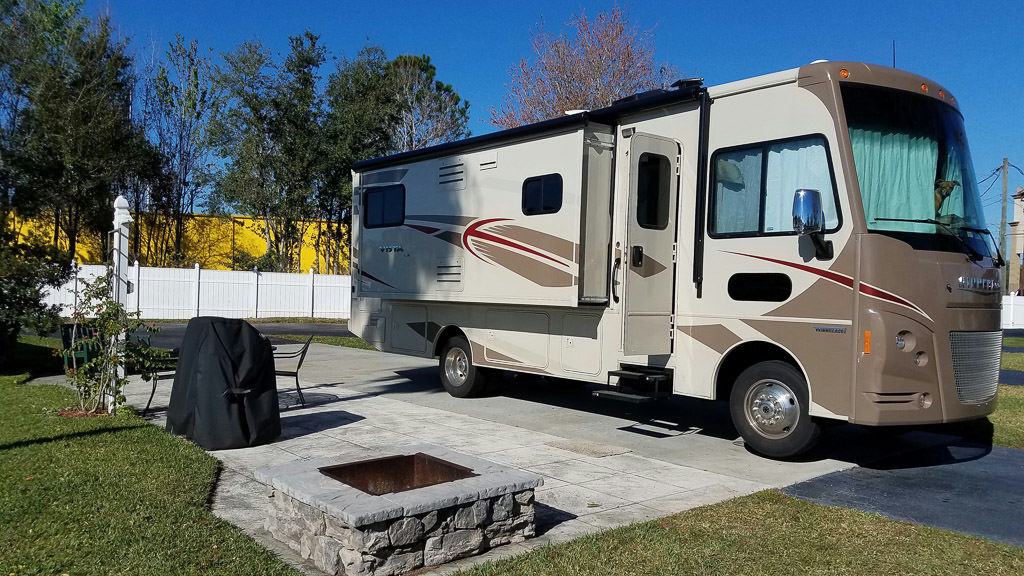 Winnebago Vista at campsite with fire pit and table outside.
